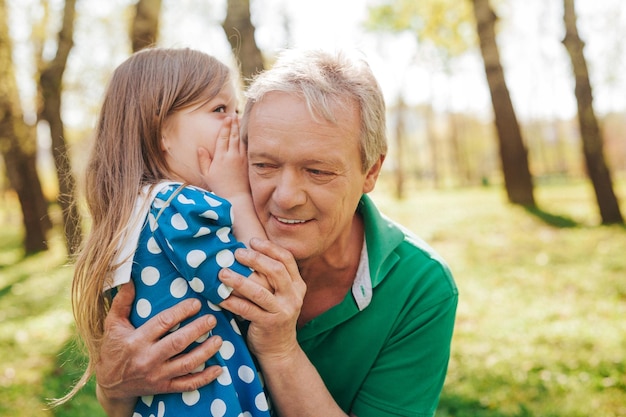 Little girl telling secret to grandpa