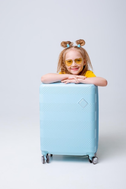 little girl traveler with a suitcase on a white background