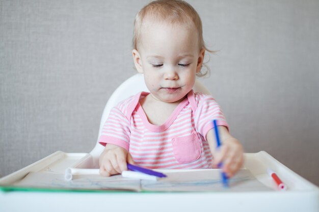 A little girl tries to draw with felttip pens