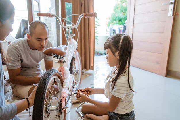 Little girl unboxing new bike with mom and dad