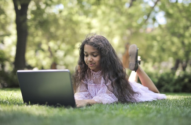 little girl uses a computer in a park