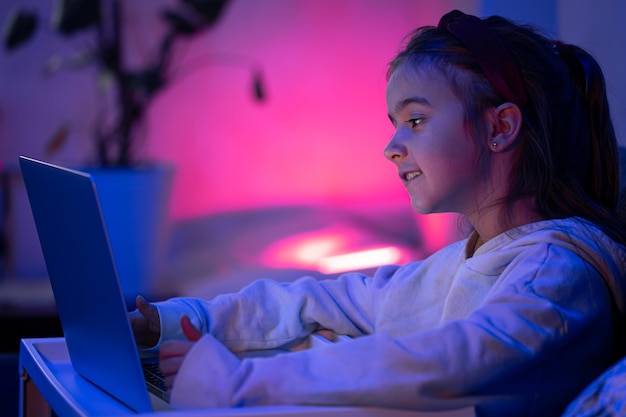 A little girl uses a laptop late at night