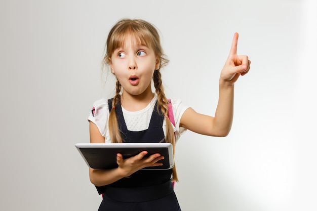 The little girl using the tablet on the white wall background