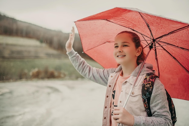 Little girl waiting for bus on rain day