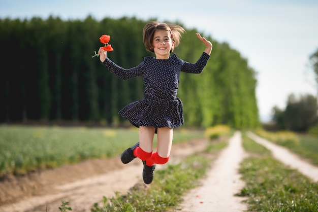 Little girl walking in nature field wearing beautiful dress