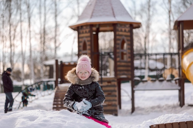 Little girl walks outdoors on winter snowy day in park