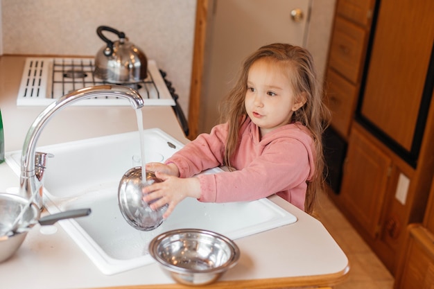 Little girl washing dishes in the kitchen of a travel trailer