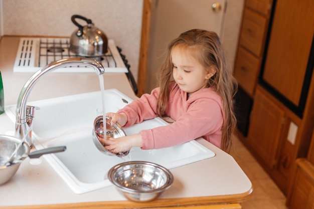 Little girl washing dishes in the kitchen of a travel trailer