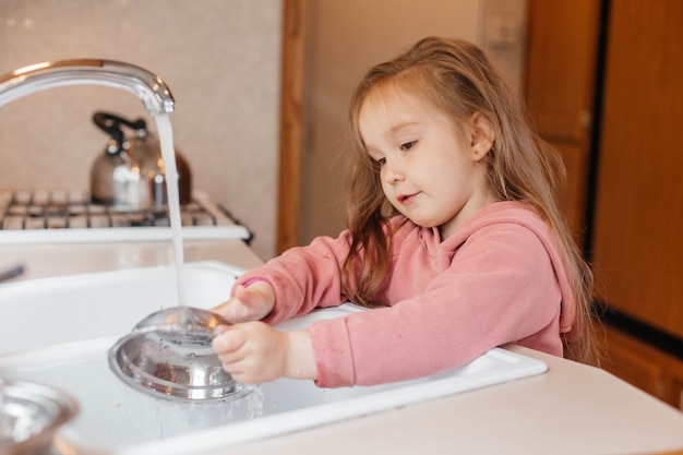 Little girl washing dishes in the kitchen of a travel trailer