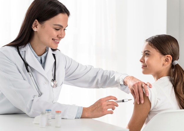 Little girl watching the doctor as she is vaccinating her