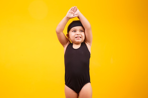 Little girl wearing beach outfit on yellow wall