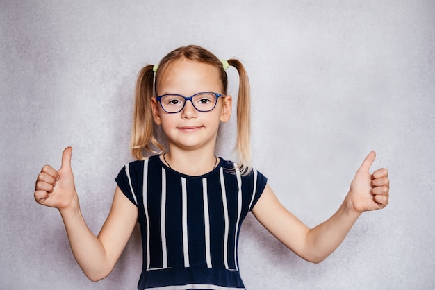 Little girl wearing eyeglasses with her thumbs up, children's Pediatric Ophthalmology, common eye problems in children