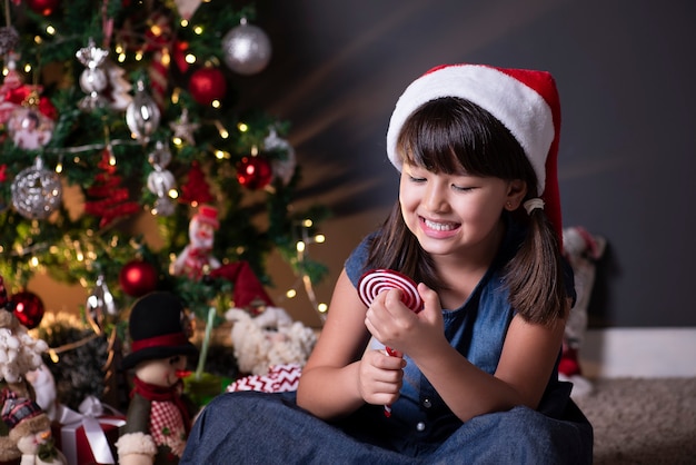 Little girl wearing Santa hat in Christmas decoration.