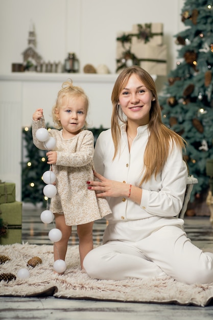 A little girl in white dress sitting with mum. 