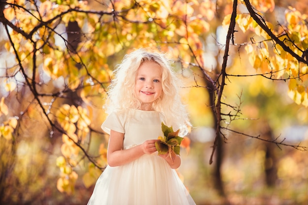 A little girl in white dress who smiles on park