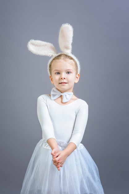 Little girl in white Easter bunny costume on gray 