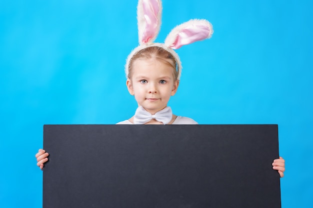 Little girl in a white rabbit costume with blank placard or poster