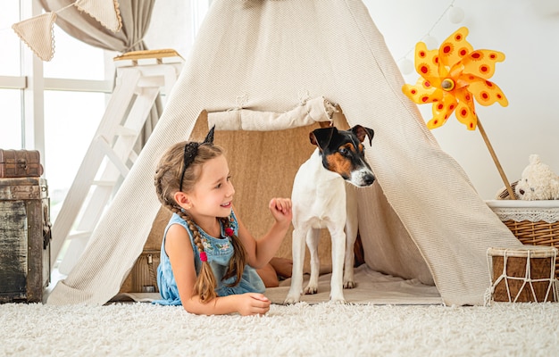 Little girl in wigwam with fox terrier