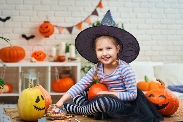 A little girl in a witch costume sitting at a table