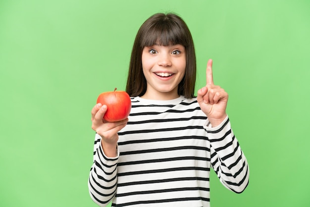 Little girl with an apple over isolated chroma key background pointing up a great idea