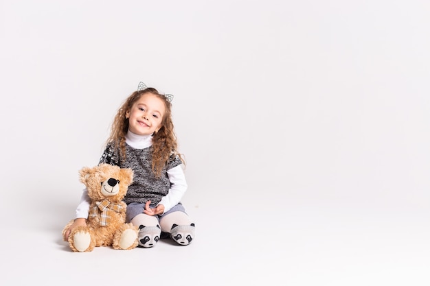 little girl with bear standing on white