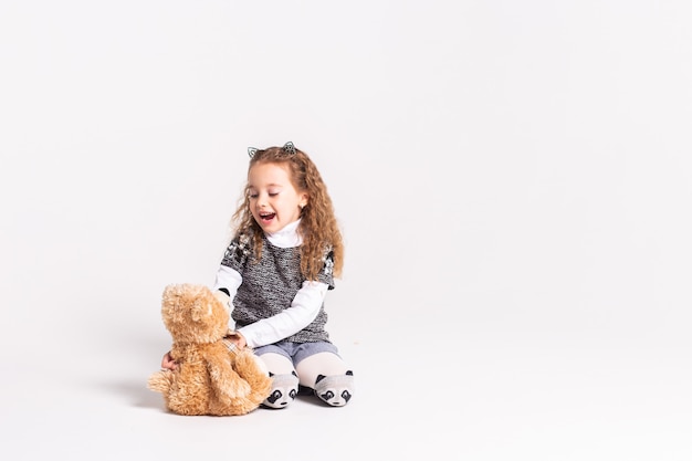 little girl with bear standing on white