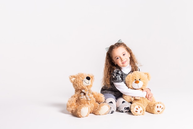 little girl with bear standing on white