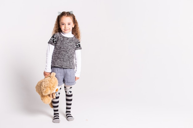 little girl with bear standing on white