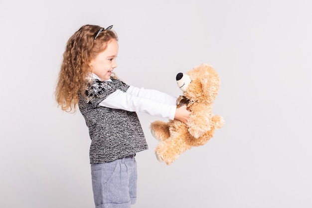 little girl with bear standing on white