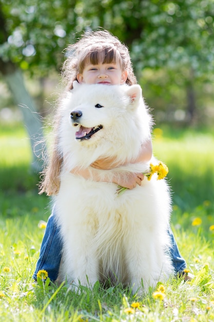 Little girl with a big white dog in the park.