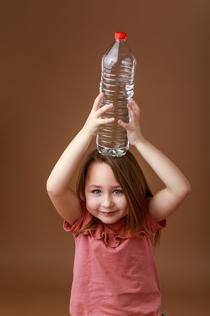 Little girl with a bottle of water on her head