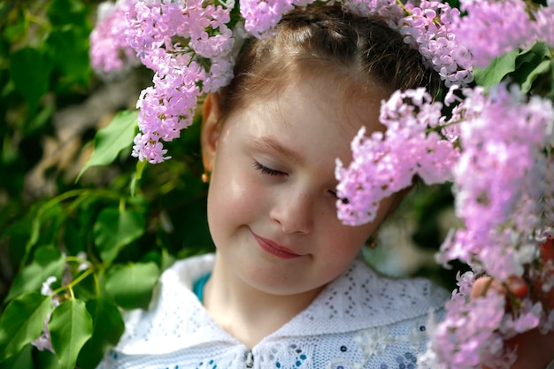 Little girl with closed eyes in a blooming lilac