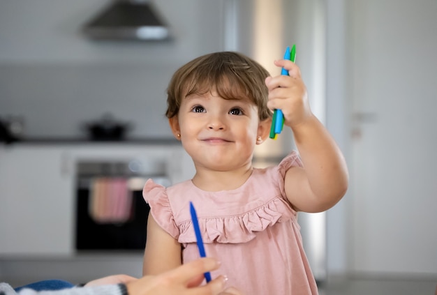 little girl with colored crayons while painting at home