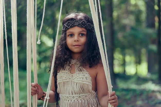 Little girl with dark curly hair dressed as a native in the forest