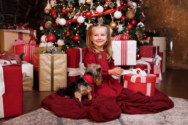 Little girl with a dog at Christmas tree with Christmas gifts