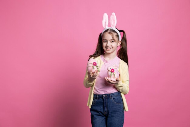 Little girl with fluffy bunny ears holds pink easter arrangements