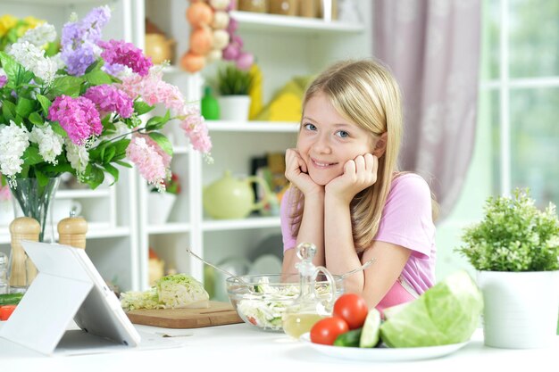 Little girl with fresh salad in glass bowl