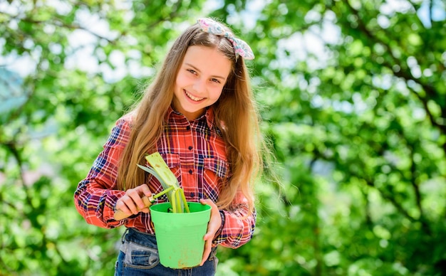 Little girl with gardening tools earth day summer farm Happy childhood spring village country little girl kid in forest ecology environment Happy childrens day child gardening