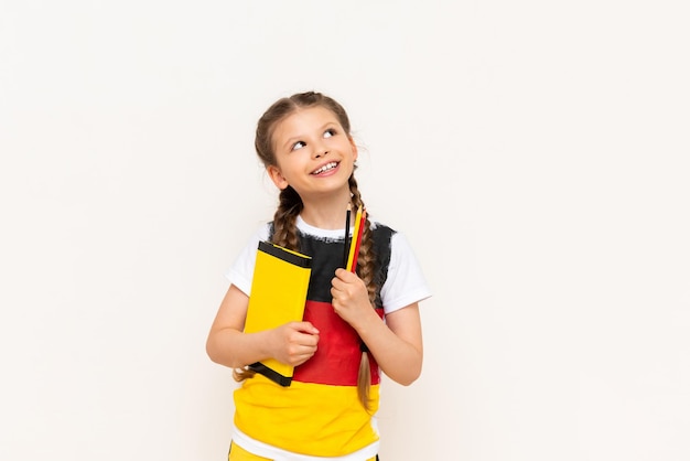 A little girl with a German flag on her Tshirt looks thoughtfully at your advertisement on a white isolated background German language courses for children