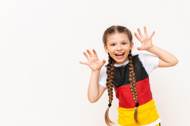 A little girl with a German flag on a Tshirt with long hair braided in pigtails on a white isolated background Language courses for children Copy space