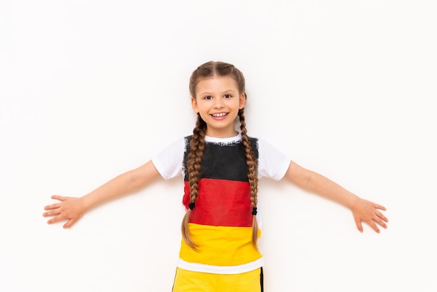 A little girl with a German flag on a Tshirt with long hair braided in pigtails on a white isolated background Language courses for children Space for copying