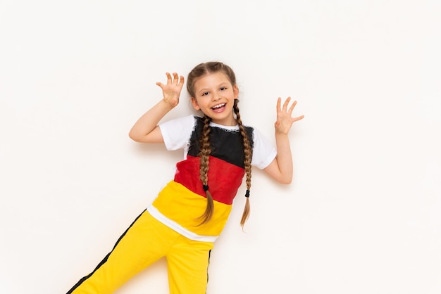 A little girl with a German flag on a Tshirt with long hair braided in pigtails on a white isolated background Language courses for children Space for copying