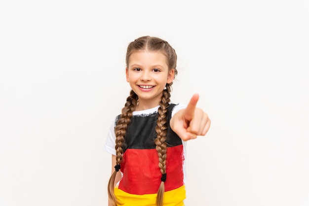 A little girl with a German flag on a Tshirt with long hair braided in pigtails on a white isolated background Language courses for children Space for copying