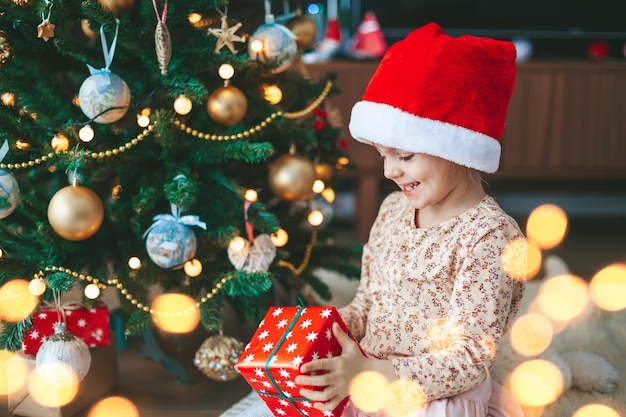 Little girl with gift box near the Christmas tree