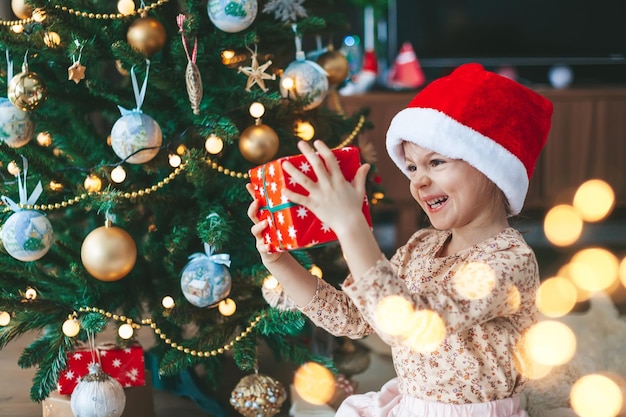 Little girl with gift box near the Christmas tree