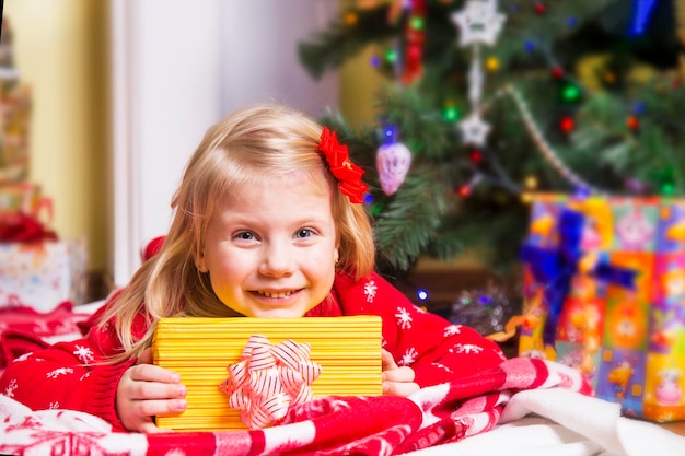 Little girl with gift under Christmas tree Happy New Year concept