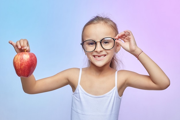 Little girl with glasses, holding a red Apple.