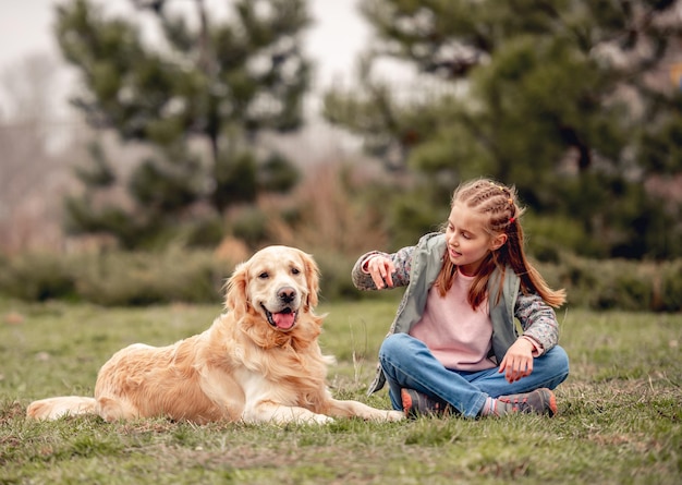 Little girl with golden retriever dog outside