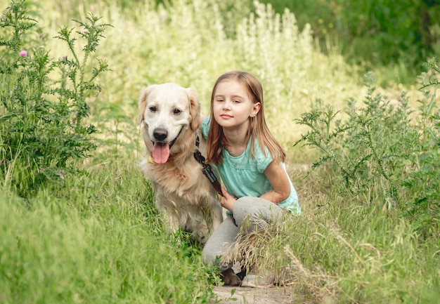 Little girl with golden retriever on meadow