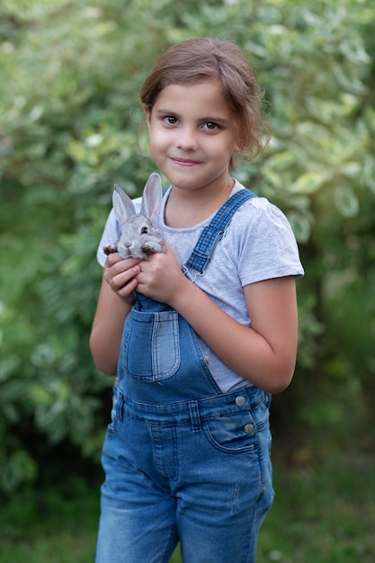 A little girl with a gray rabbit in her hands